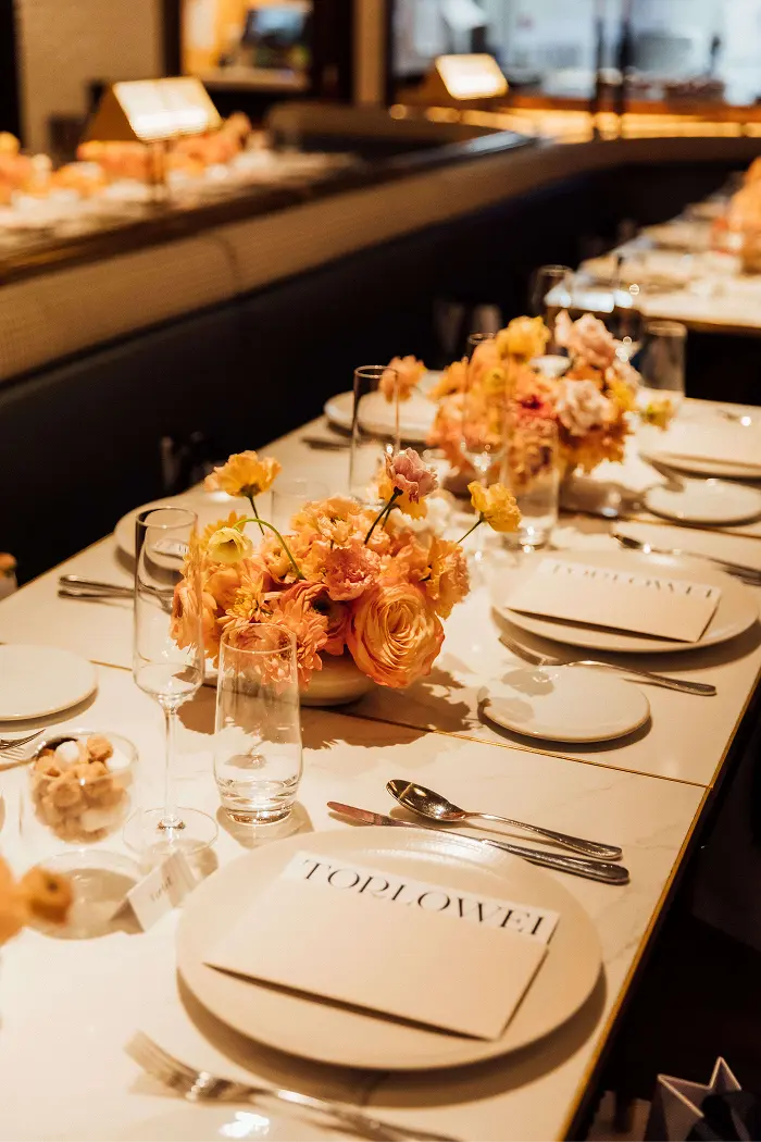 Dinner table styled with peach and yellow flowers and TOPLOWE printed menus